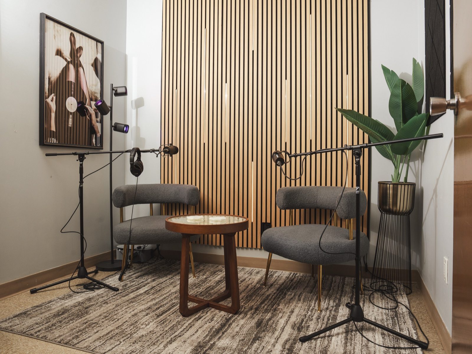 Podcast studio with lounge chairs, microphones, and a wood slat accent wall