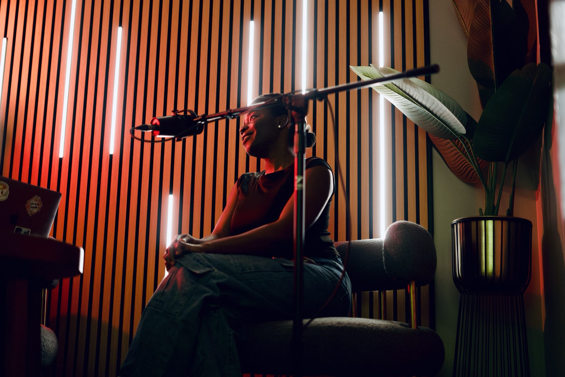 Guest on a boom microphone against a warm-lit wood slat wall in the podcast room