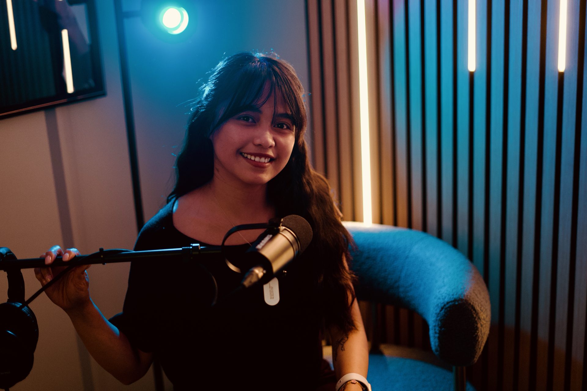 Smiling host at the microphone in the podcast room