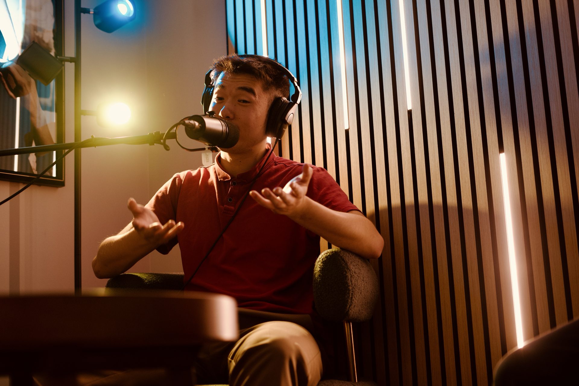 Host speaking into a broadcast microphone in the podcast room