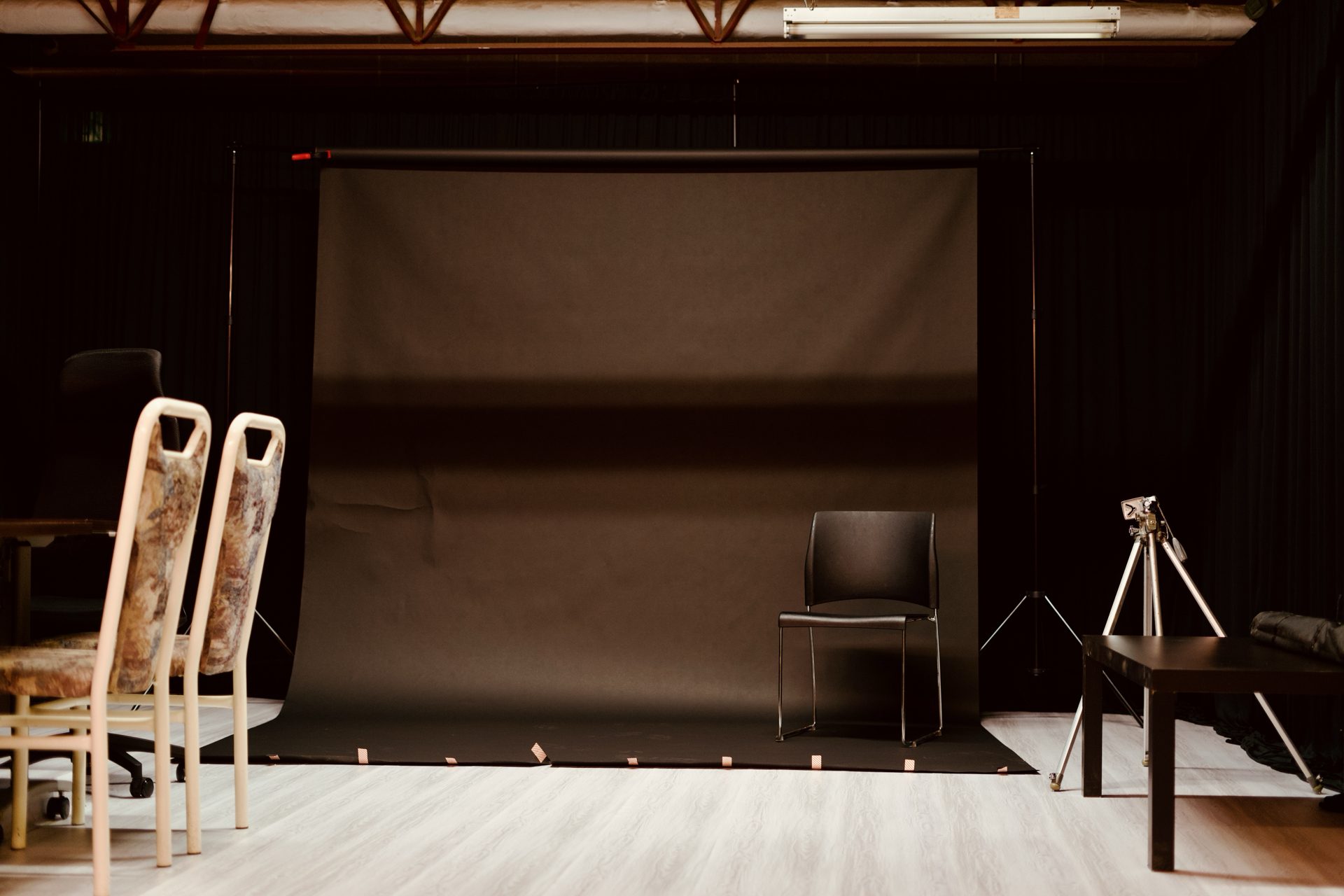 Photography studio with a seamless backdrop, studio seating, and a tripod