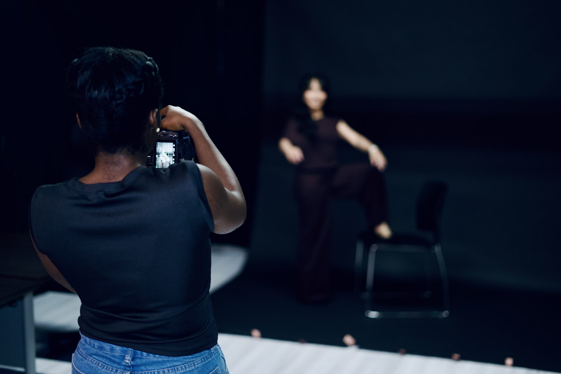 Photographer shooting a model against a black backdrop in the photography studio