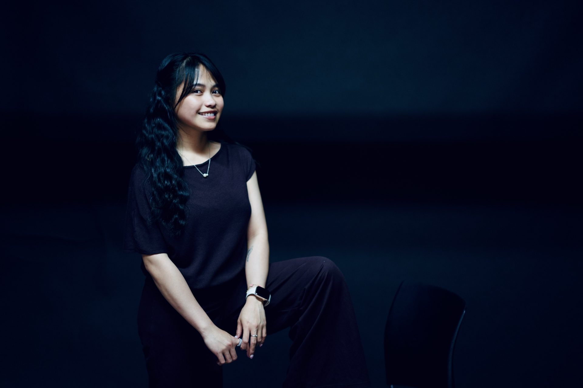 Studio portrait of a seated model against a black backdrop